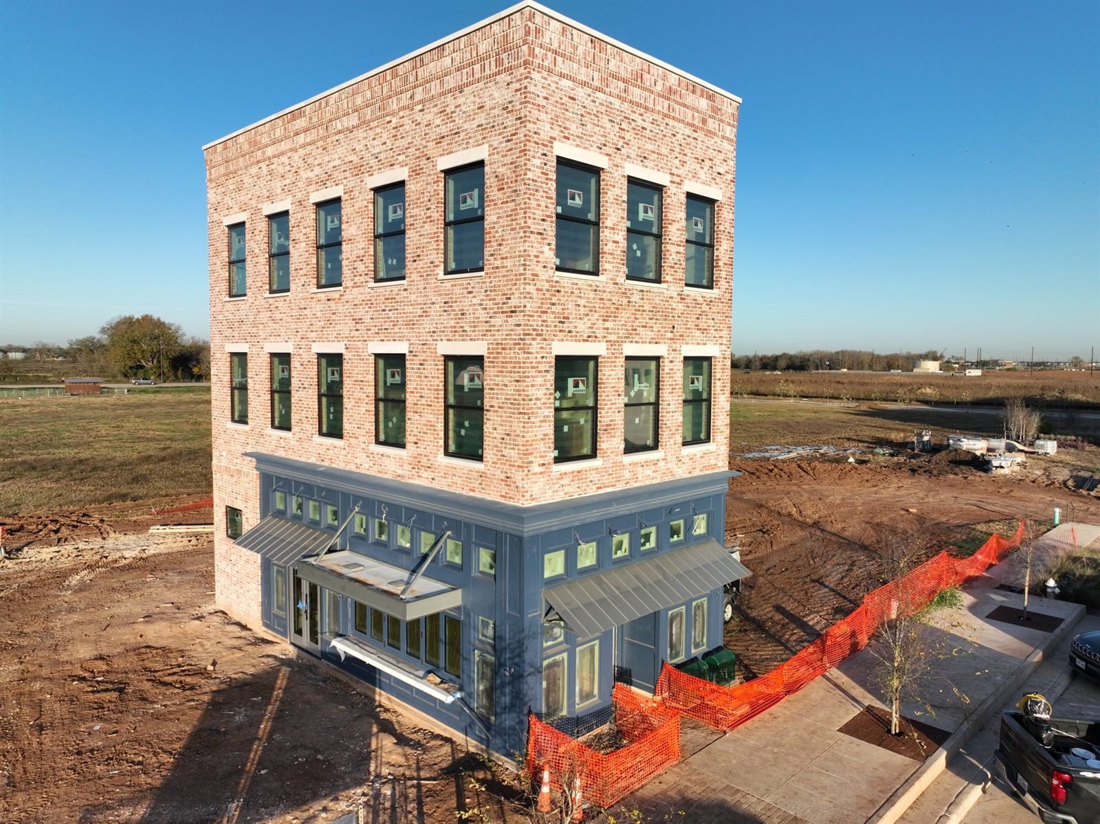 A newly built three-story brick building on a single lot, shopfront below and homes above
